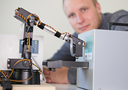 Referenz: Mitarbeiter vor einem prototypischen Roboterarm der Dosimeter zur Auswertung bewegt